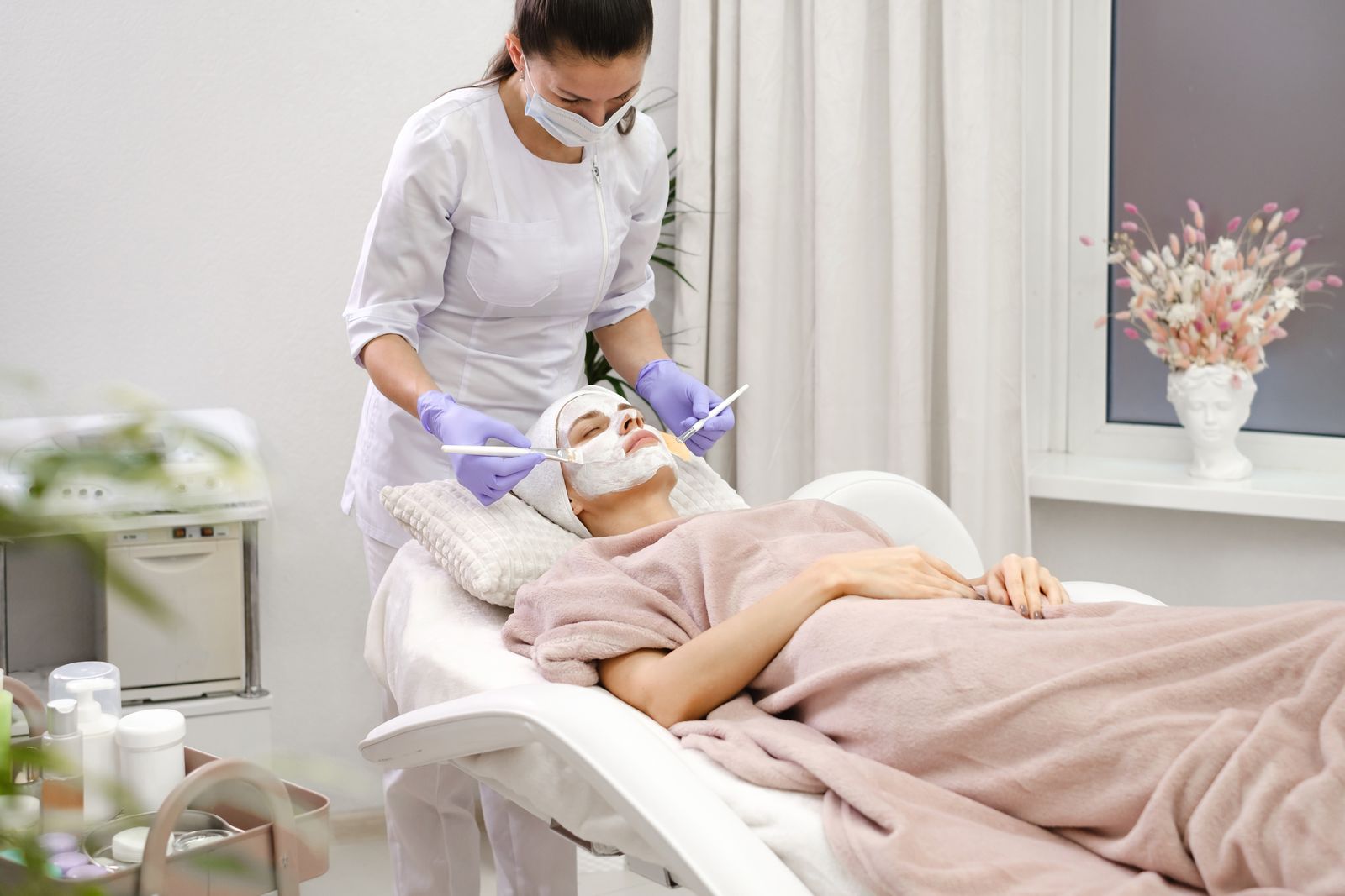 Client relaxing during a facial treatment in a bright, calm treatment room